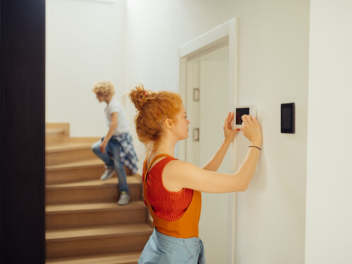 Woman adjusting thermostat settings